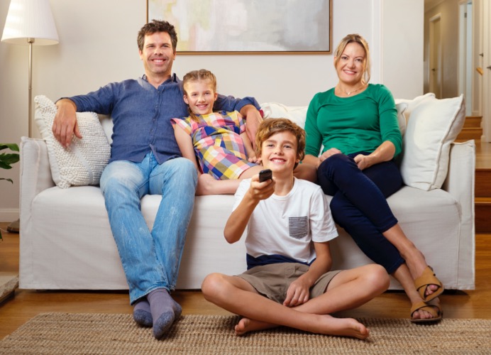 Young family on the couch watching the latest release movies with Telstra entertainment